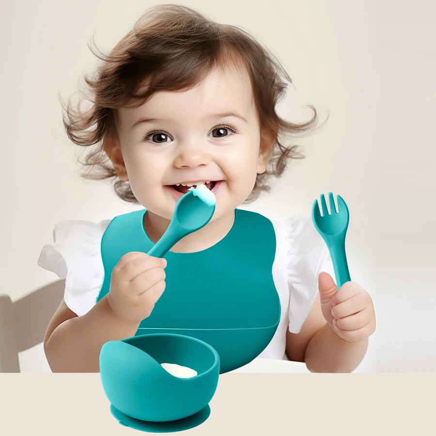 Eating from the teal suction bowl wearing the matching bib