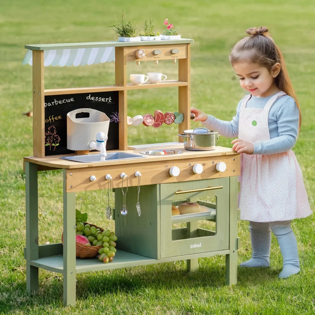 Child playing with a wooden play kitchen set outdoors on grass