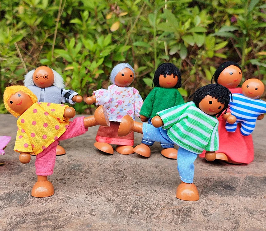 Set of colorful wooden dolls with different outfits on a natural stone surface.