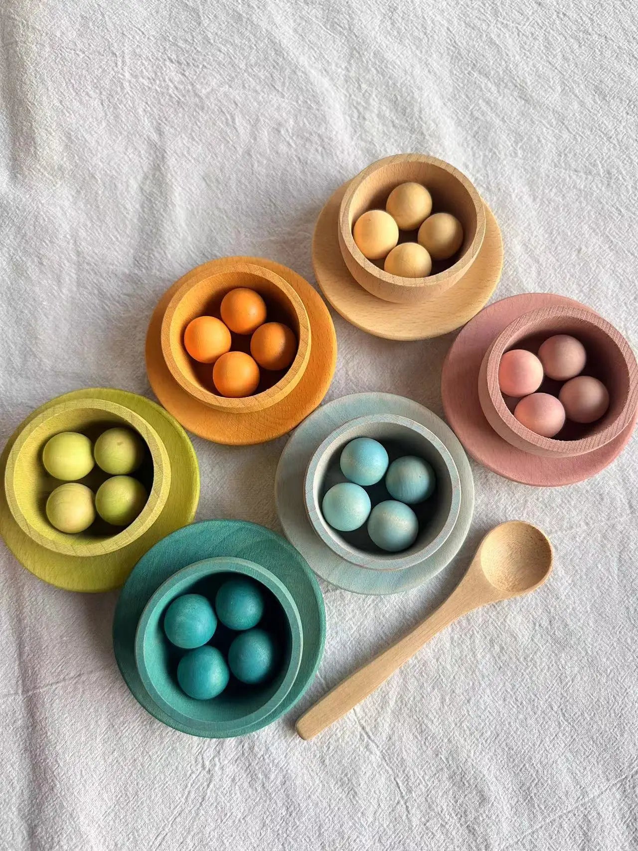 Colorful bowls with wooden spoons on a textured white surface