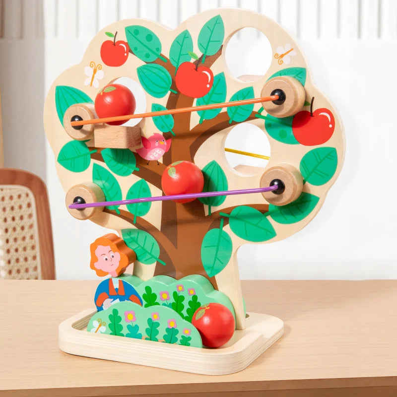 Wooden toy apple tree with apples and a character on a wooden table.