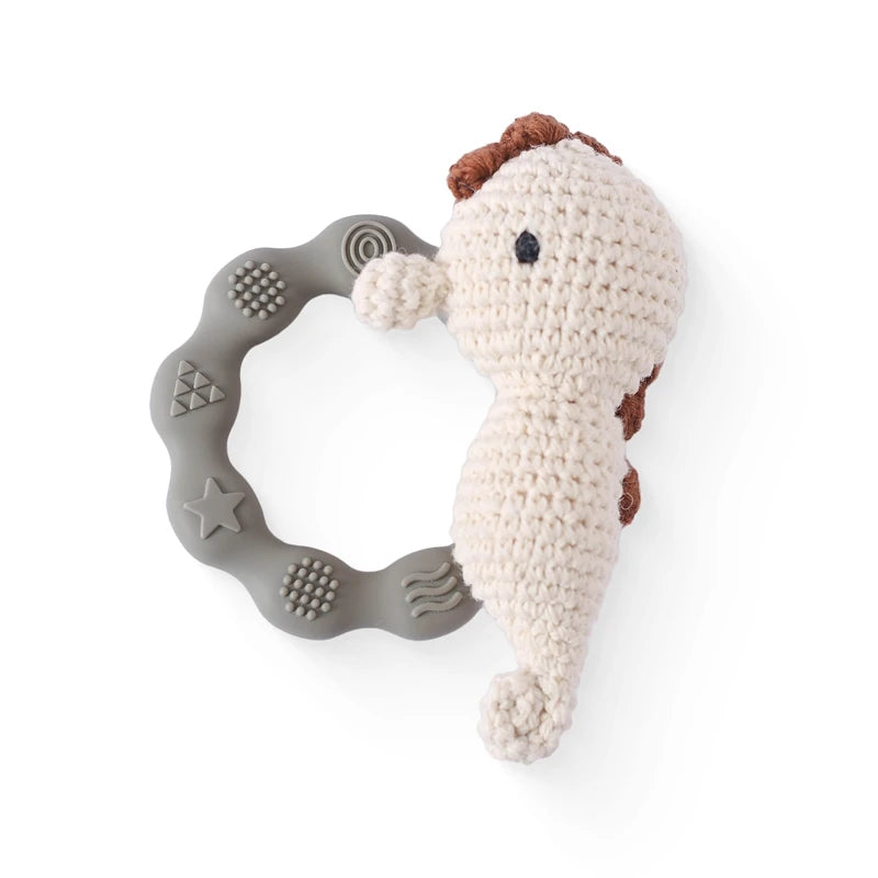 Crocheted seahorse toy with a gray teething ring on a white background