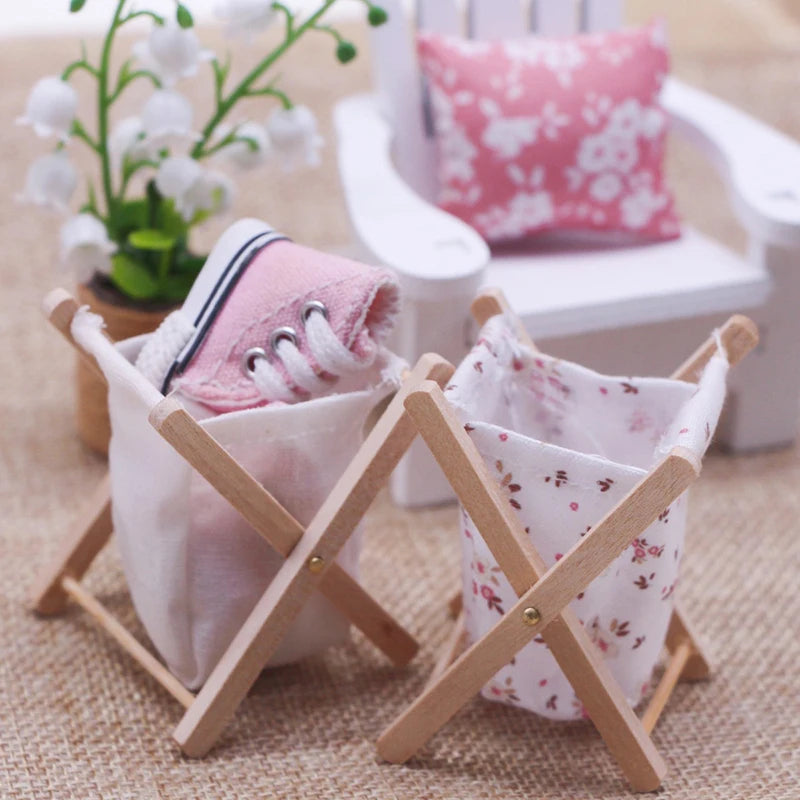 Small wooden basket with pink shoes and a floral bag on a textured surface.