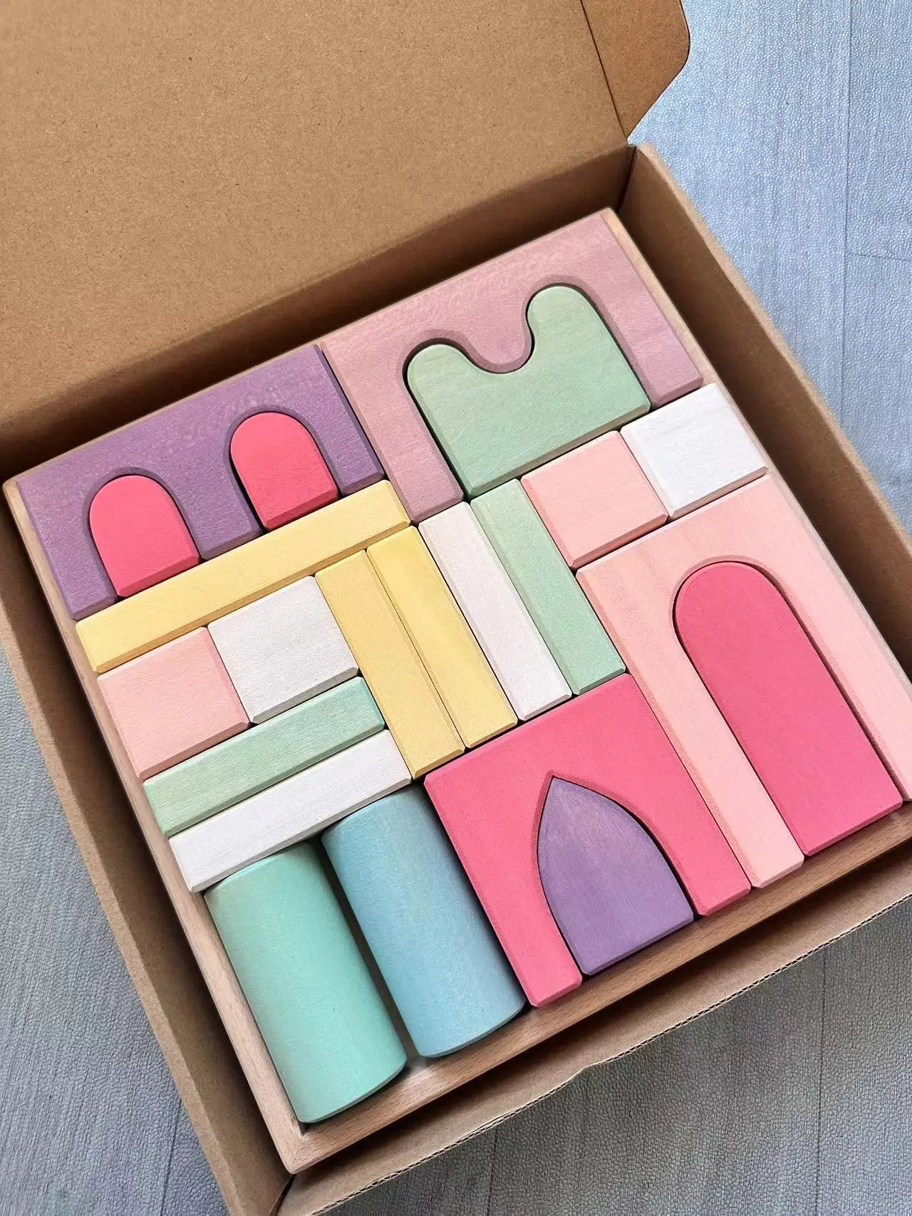 Pastel-colored wooden blocks in a box on a light gray surface