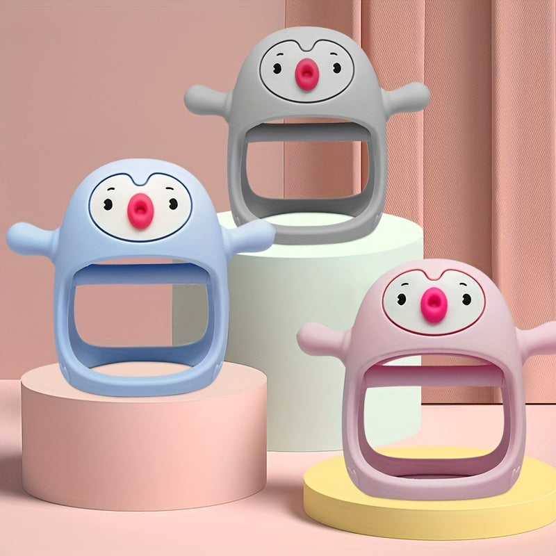 Three cartoonish baby teething toys in blue, gray, and pink on colorful cylindrical platforms with a soft pink background.