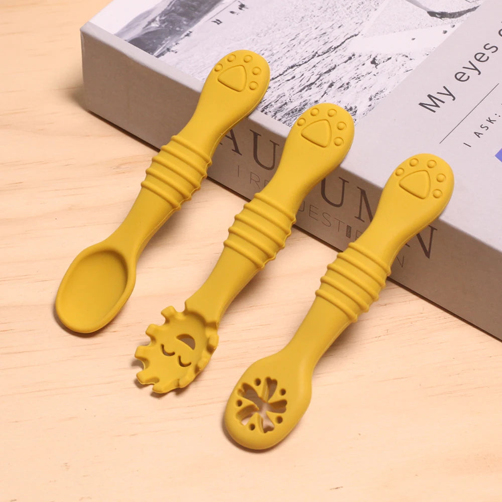 Three yellow silicone spoons with unique designs on a wooden surface.