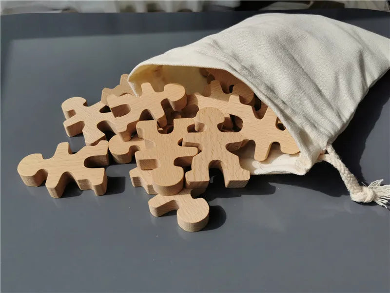 Wooden puzzle pieces spilling out of a cloth bag on a gray surface