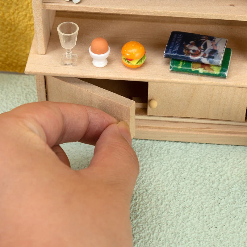 Hand opening a miniature wooden cabinet with food items on a light green surface
