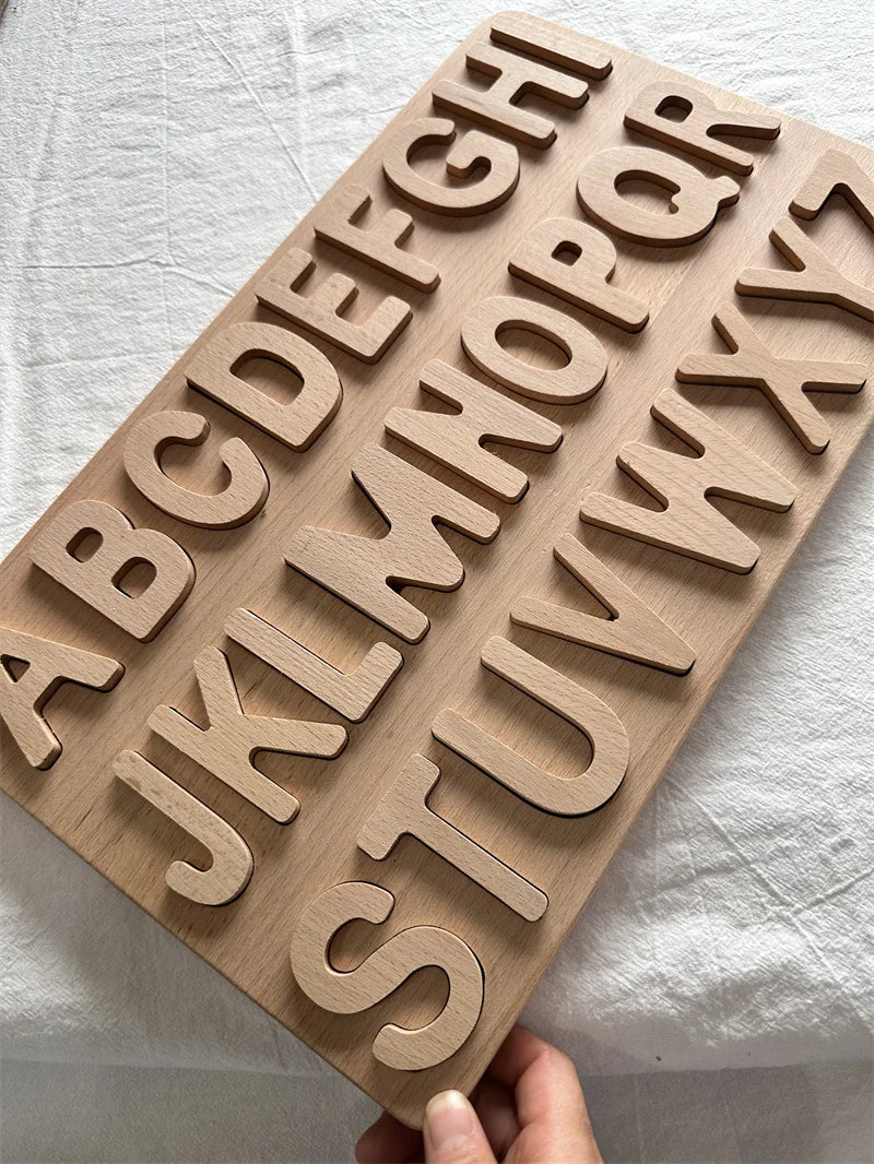 Wooden letter board with cut-out letters held by a hand on a light background