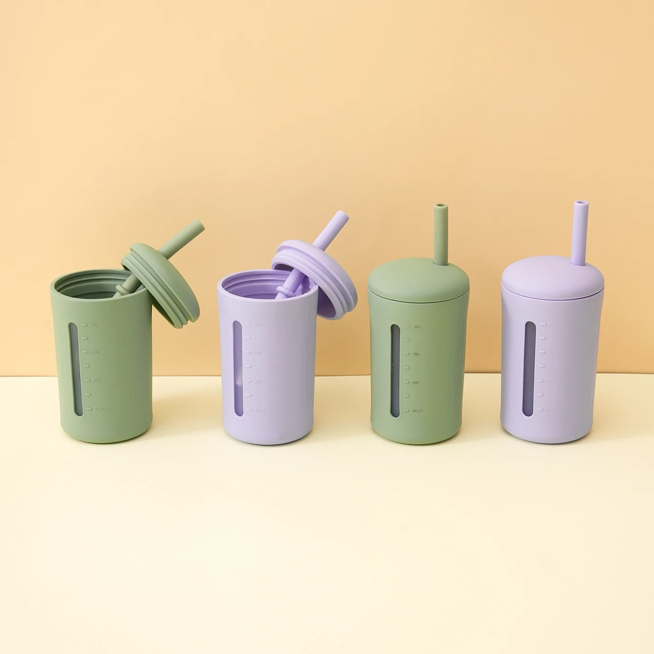 Lavender and sage silicone straw cups with lids on a table