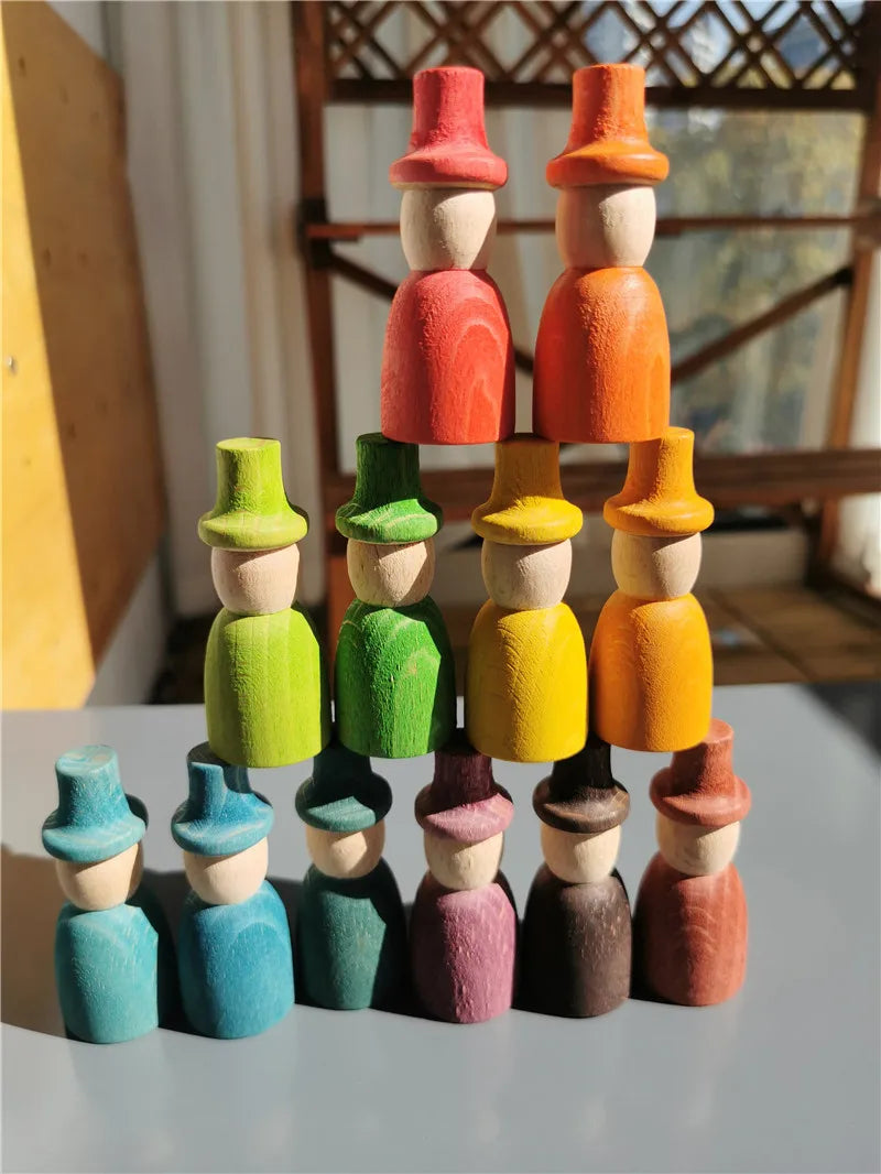 Stack of colorful wooden figures with hats on a light surface.