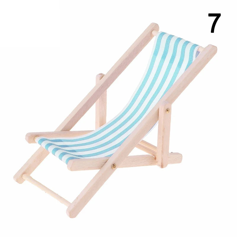 Miniature wooden deck chair with a blue and white striped fabric on a white background