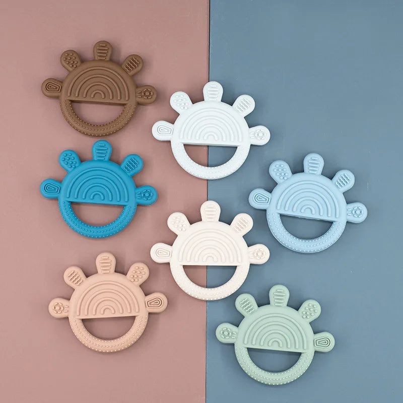 Rainbow sun teethers laid out on a two-tone background