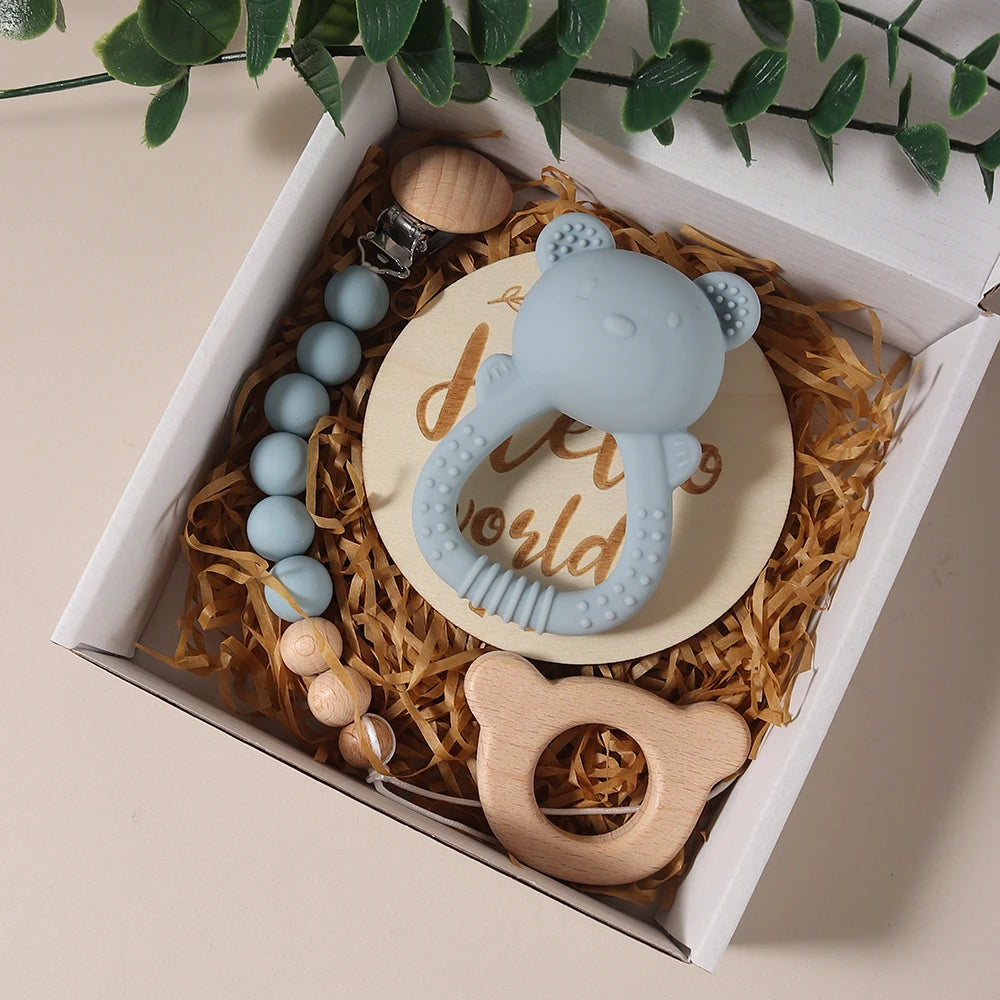 Set of baby teething toys including a silicone teether, wooden ring, and beaded necklace in a decorative box.