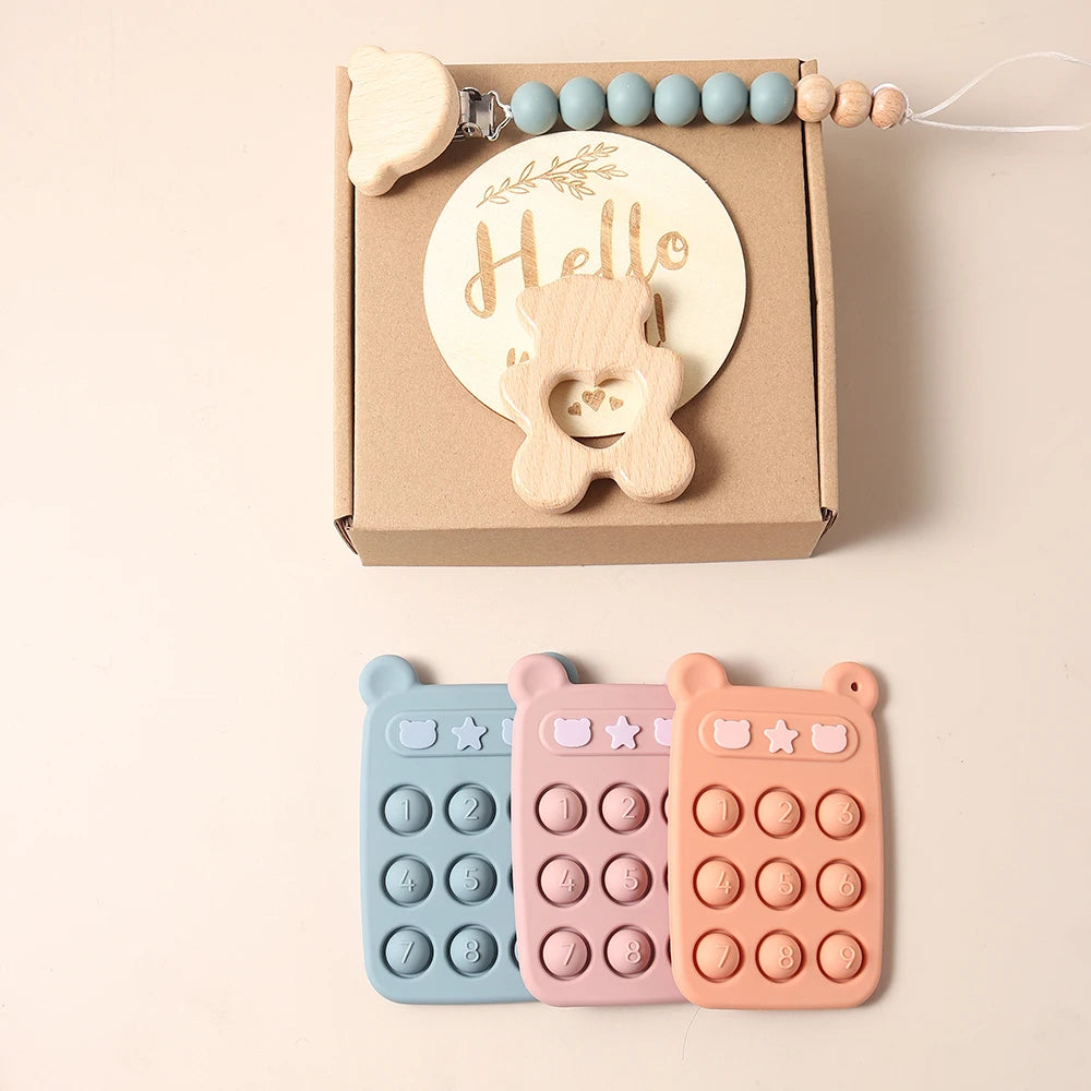 Three colorful fidget toys in front of a cardboard box with a baby teether and 'Hello' sign.