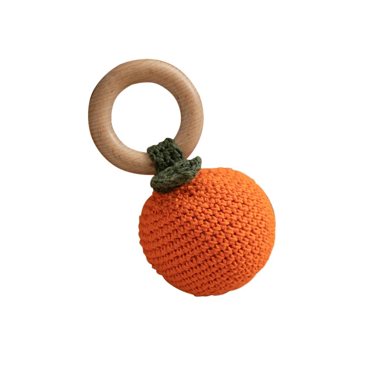 Crocheted orange with wooden ring on a white background