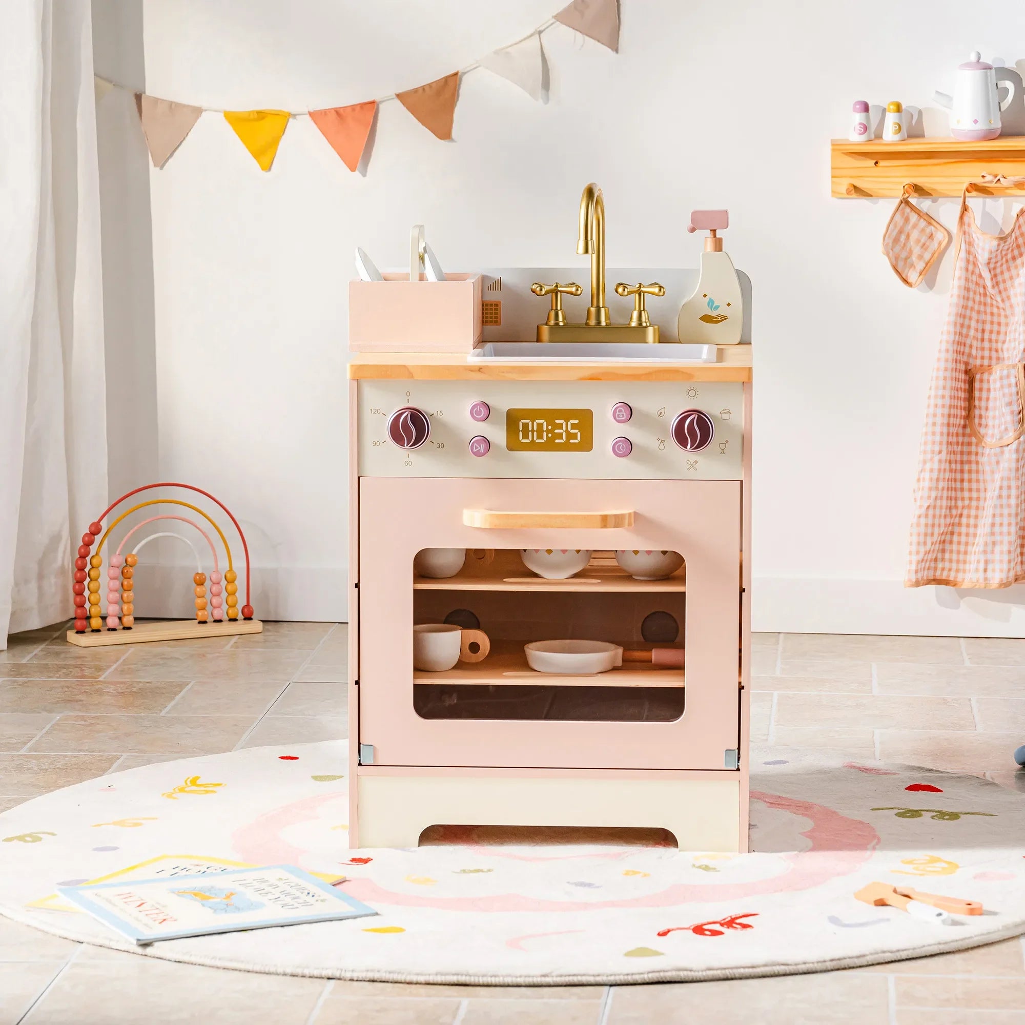 Children's play kitchen set with oven, sink, and various accessories in a room setting.