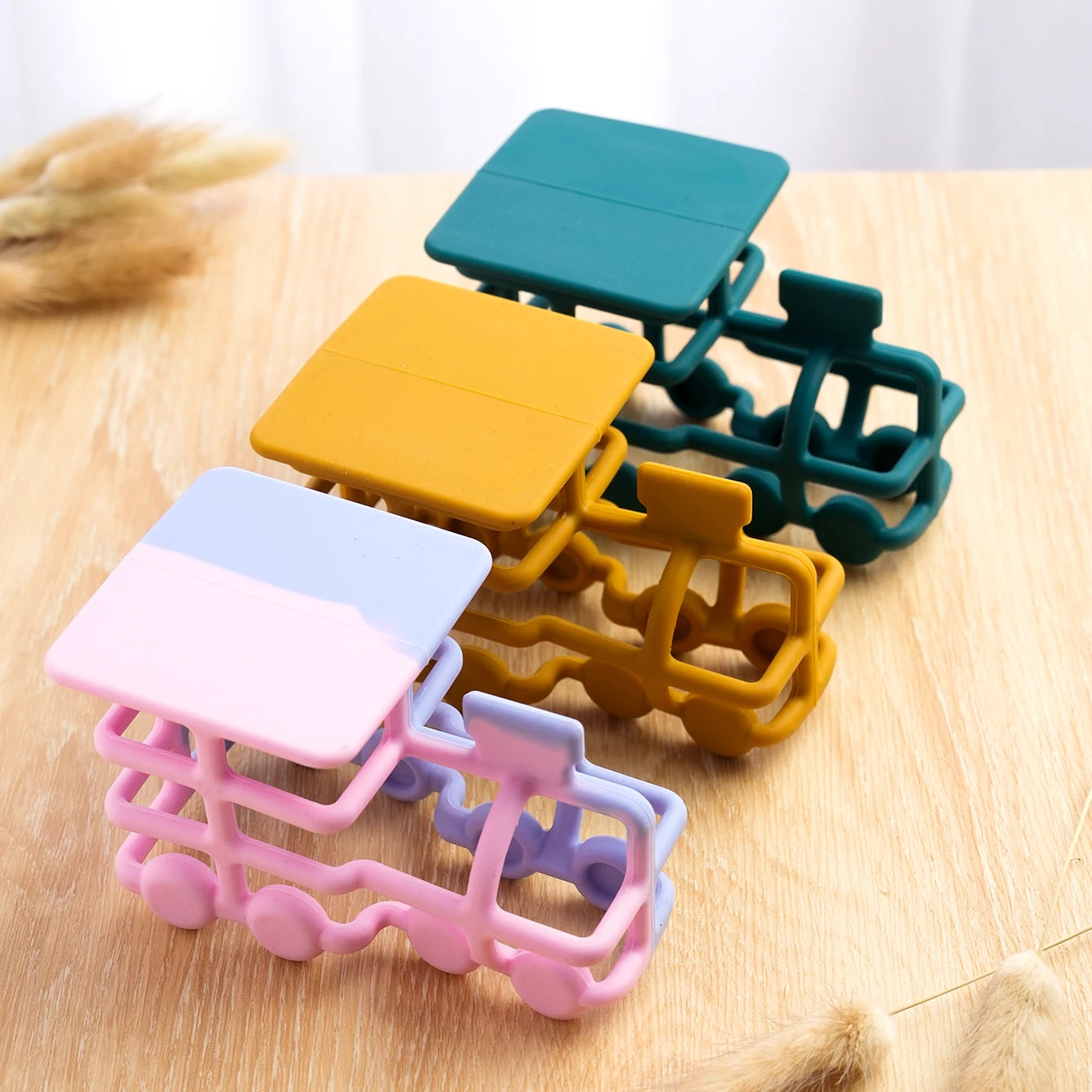 Three silicone train teethers on a wooden surface