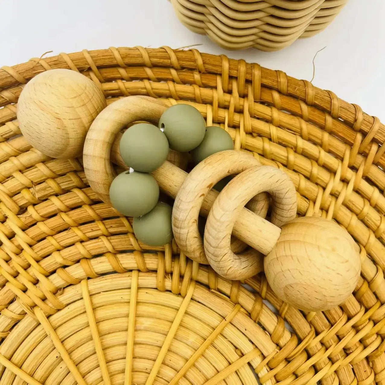 Wooden and silicone baby teething ring on a woven surface