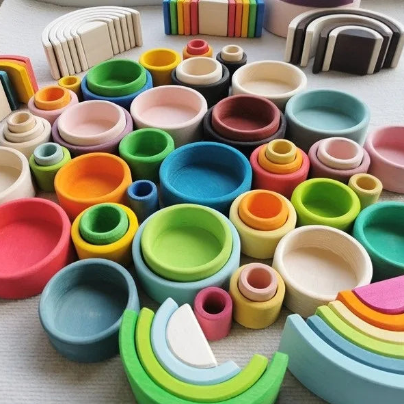 Colorful wooden toys including rainbow shapes and circular blocks on a light surface.