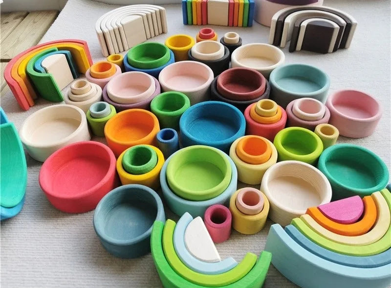 Colorful wooden toys including rainbow shapes and circular blocks on a light surface.