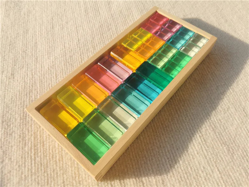 Colorful transparent blocks in a wooden box on a beige fabric background