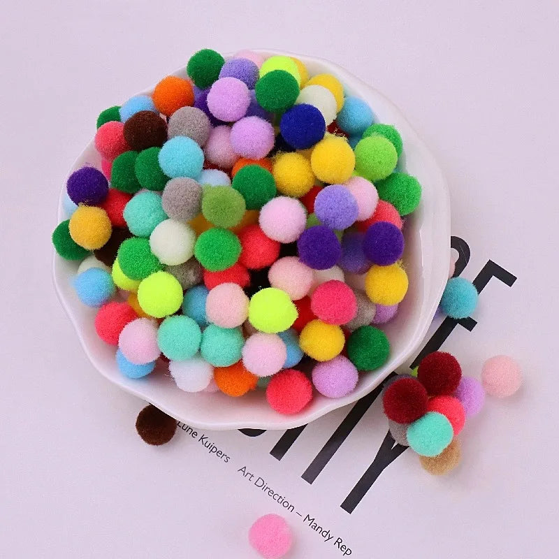 Assorted colorful pom-poms on a white plate with a magazine underneath.