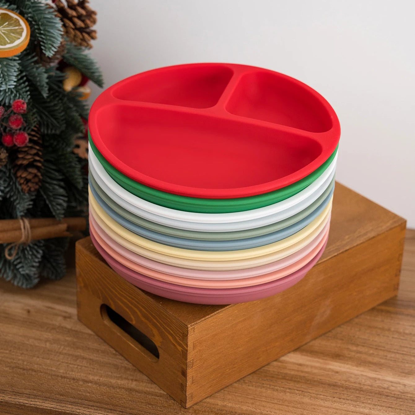 Red round silicone divided plate on top of a stack of colorful plates