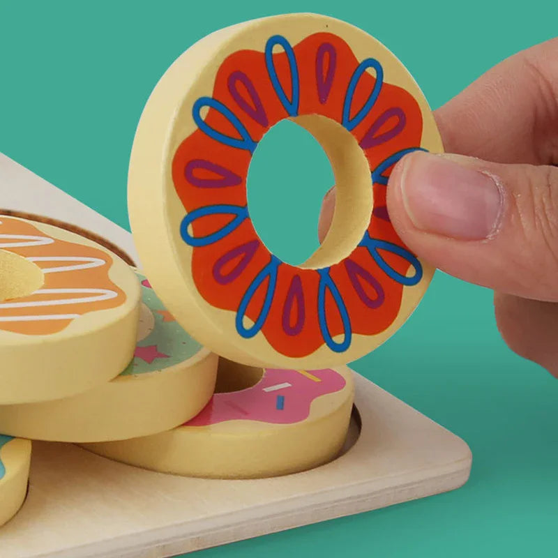 Colorful wooden toy donuts with a hand interacting with one of them on a teal background