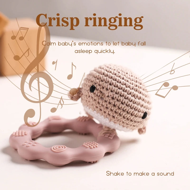Pink teething ring with a crochet toy on a light background with musical notes.