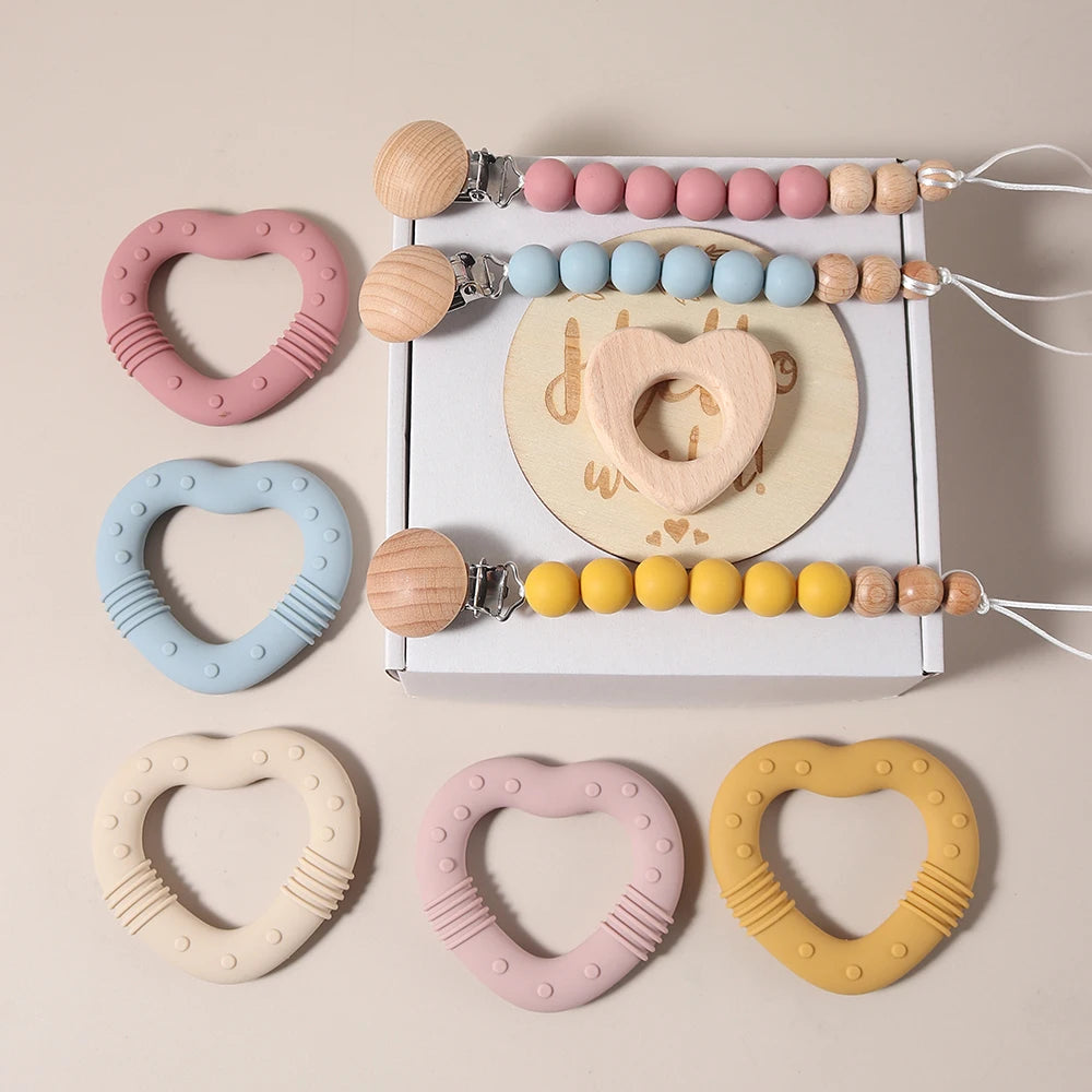 Set of colorful baby teething toys with a pacifier clip on a beige background