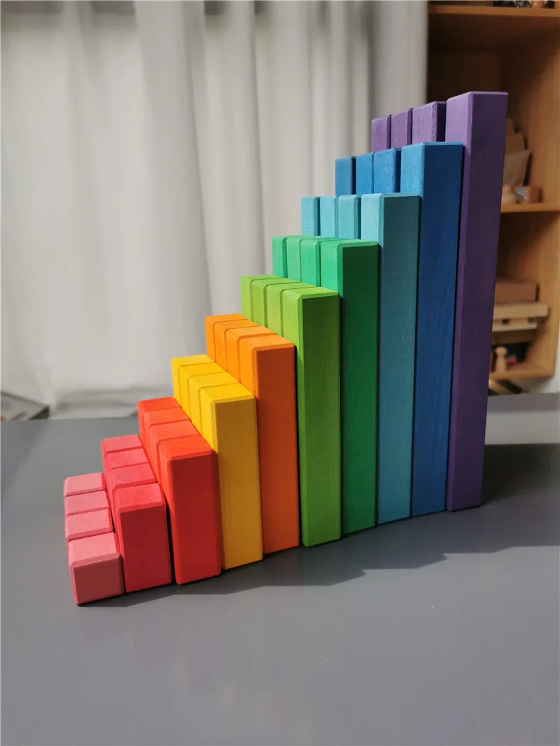 Colorful wooden blocks arranged in a pyramid shape on a gray surface.