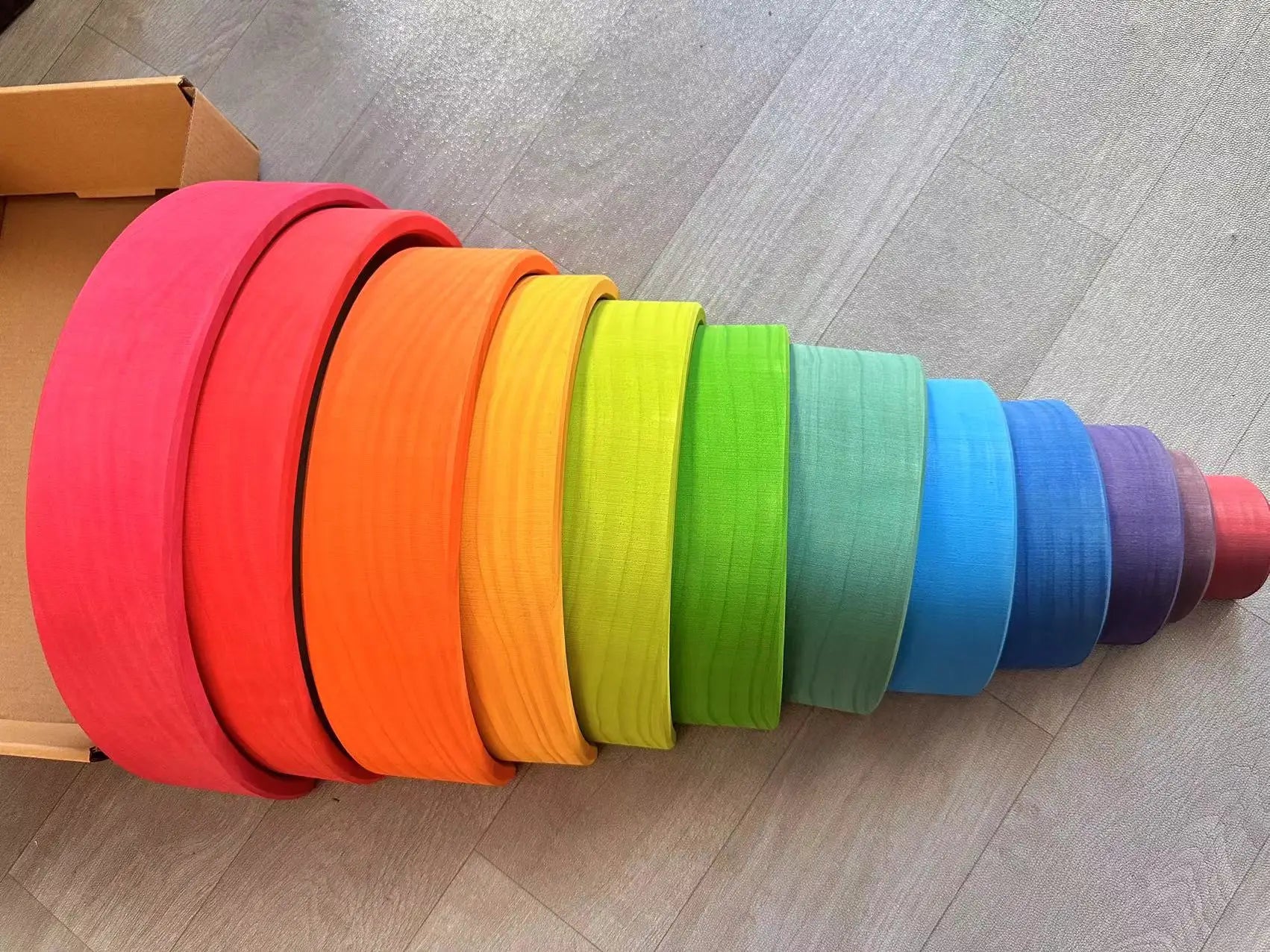 Colorful toy rings arranged in a cone shape on a wooden floor.