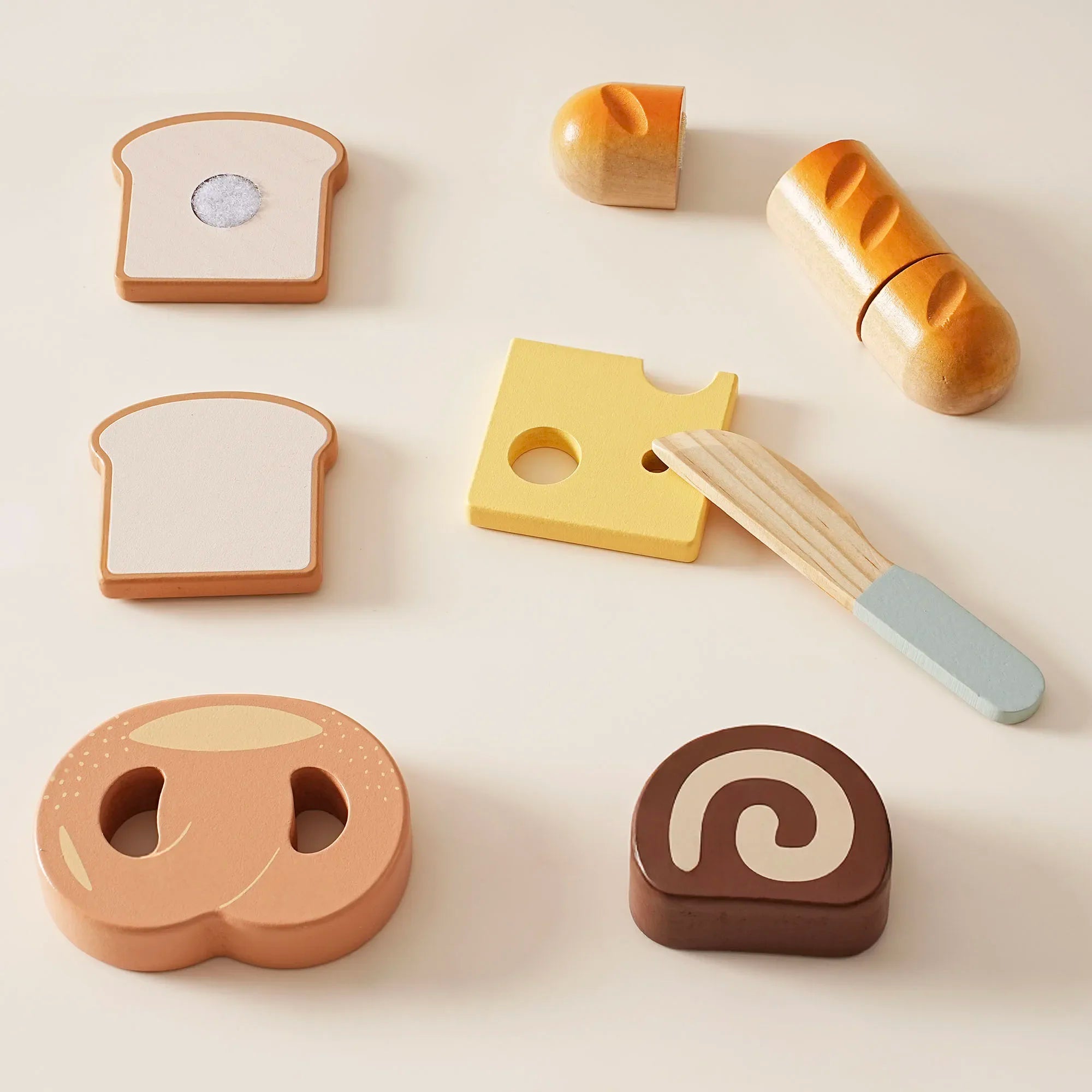 Wooden toy bread and cheese set on a light beige background
