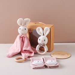 Comfort Towel Baby Gift Set featuring a knitted bunny doll, wooden ring, pink baby socks with animal face, and milestone disc in a box.