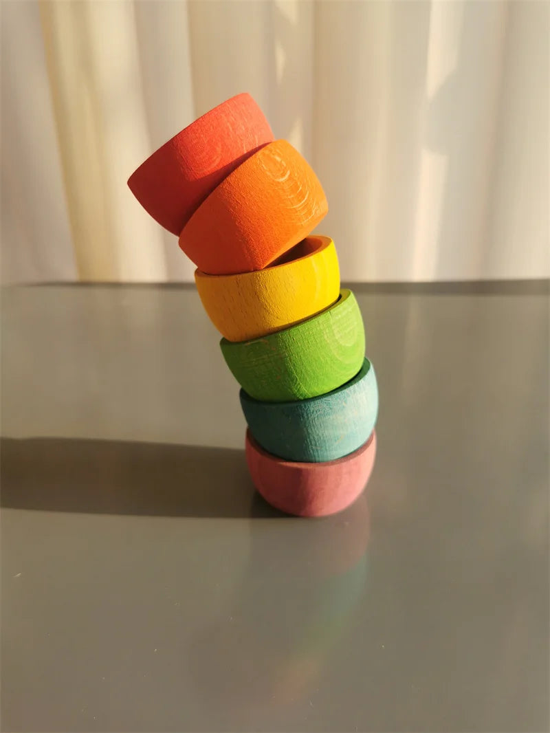 Stack of colorful wooden cups on a reflective surface with a neutral background