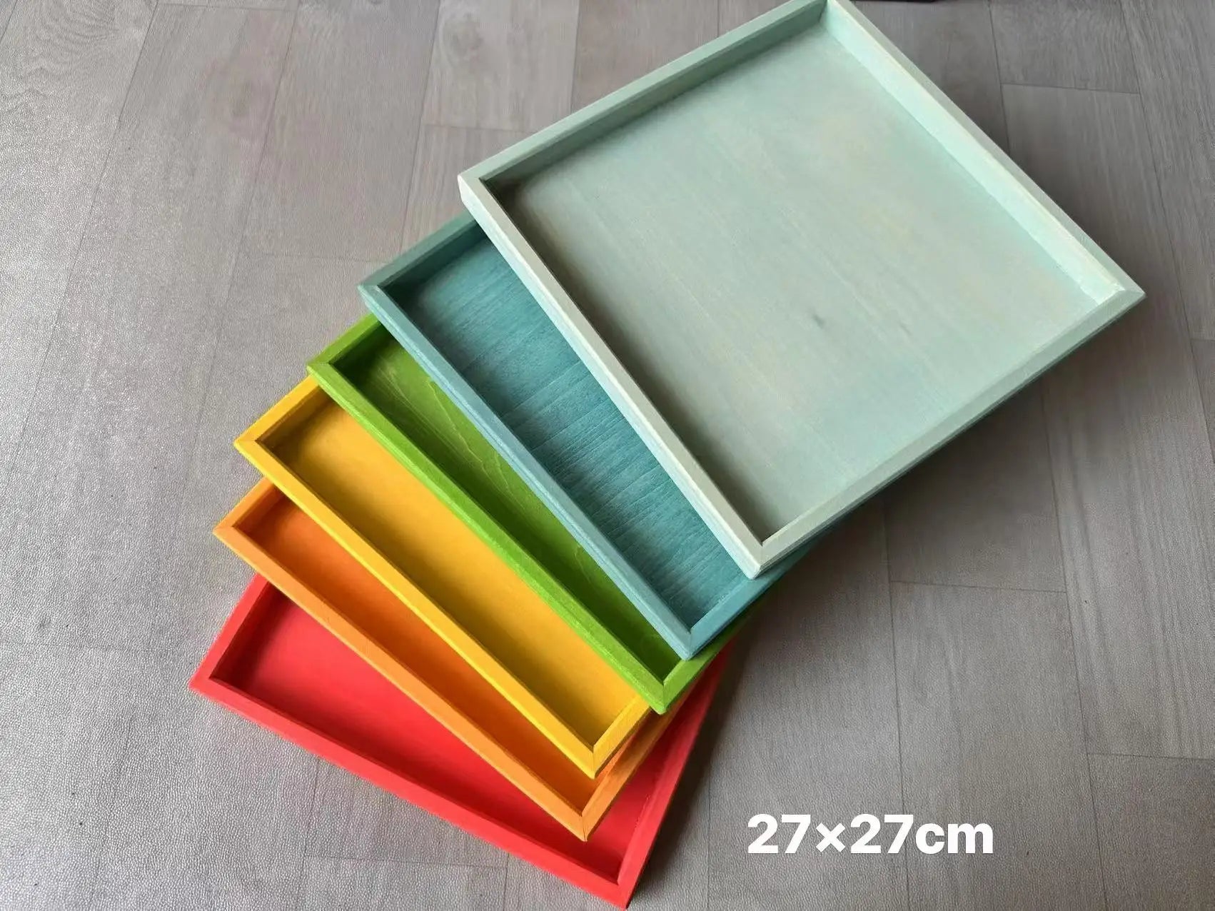 Set of colorful trays stacked on a wooden surface with dimensions indicated.