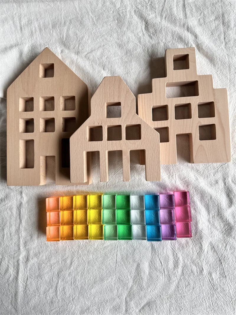 Three wooden house-shaped molds on a white fabric background with a colorful grid of squares below.