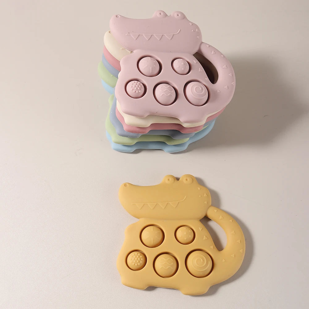 Stack of colorful cat-shaped silicone teething toys on a beige background