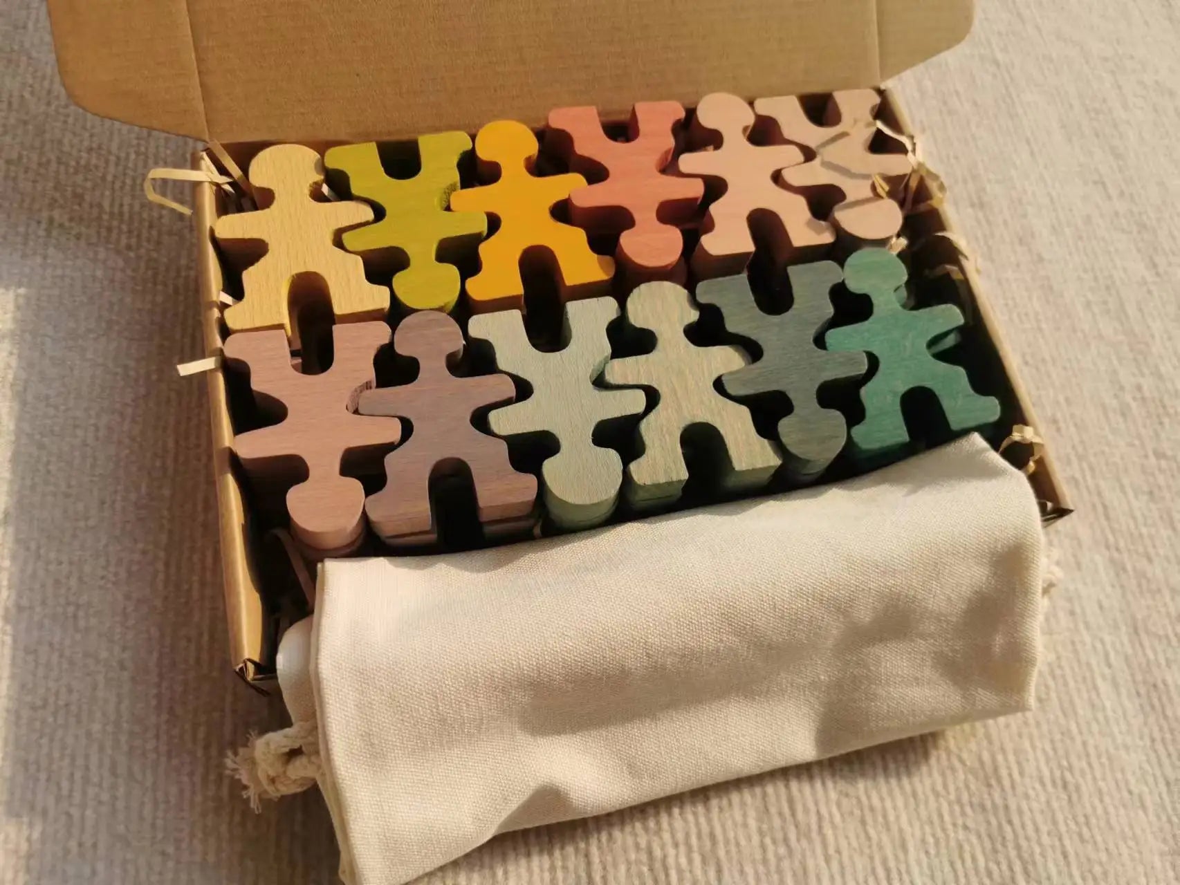 Colorful wooden puzzle pieces in a cardboard box on a beige surface