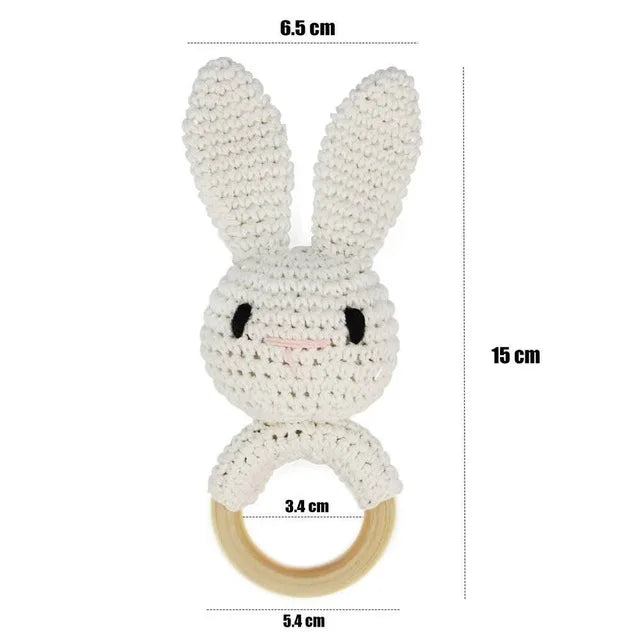 White crocheted bunny rattle with wooden ring and measurements on a white background