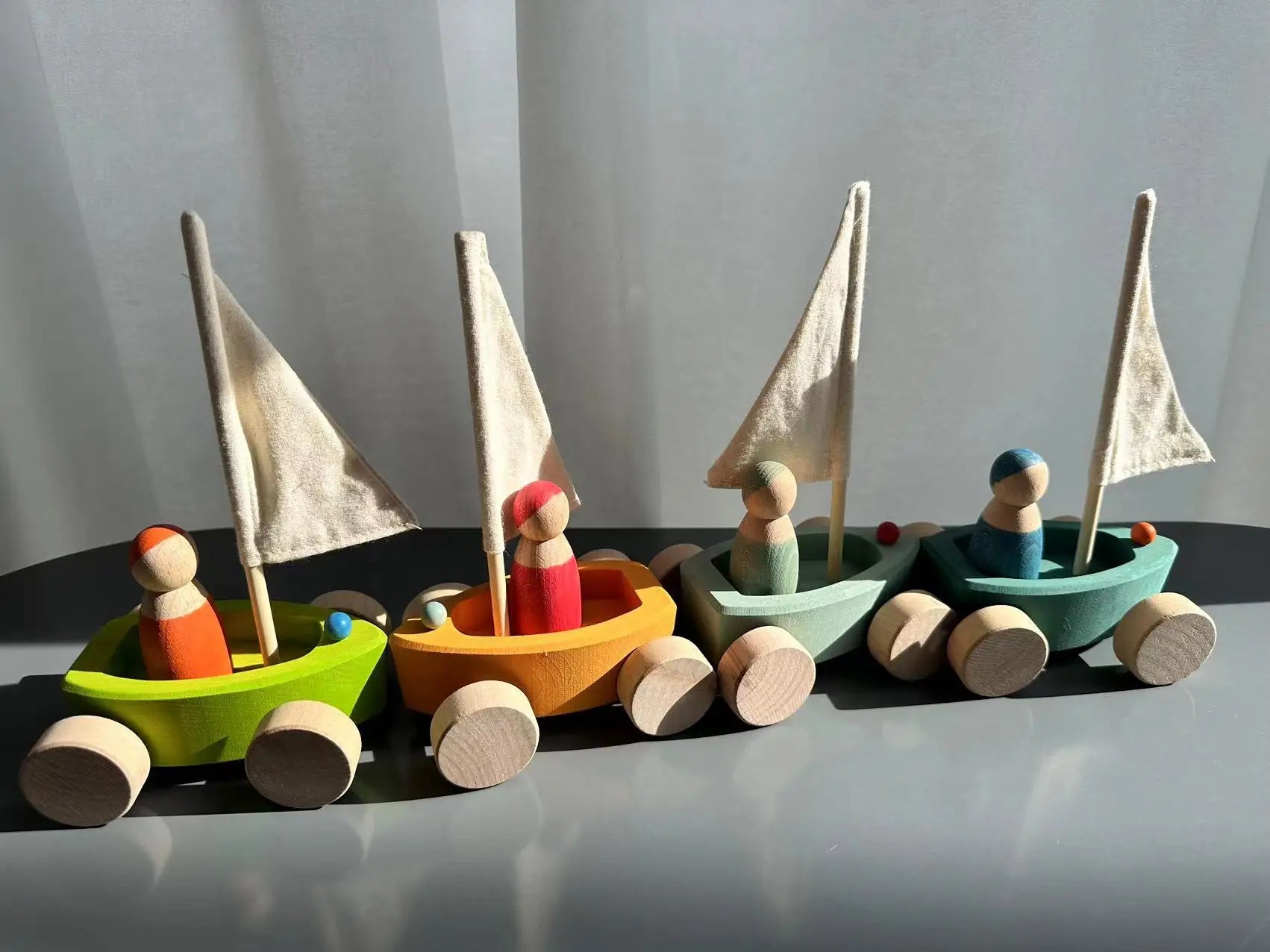 Set of colorful wooden toy boats with peg people on a plain background
