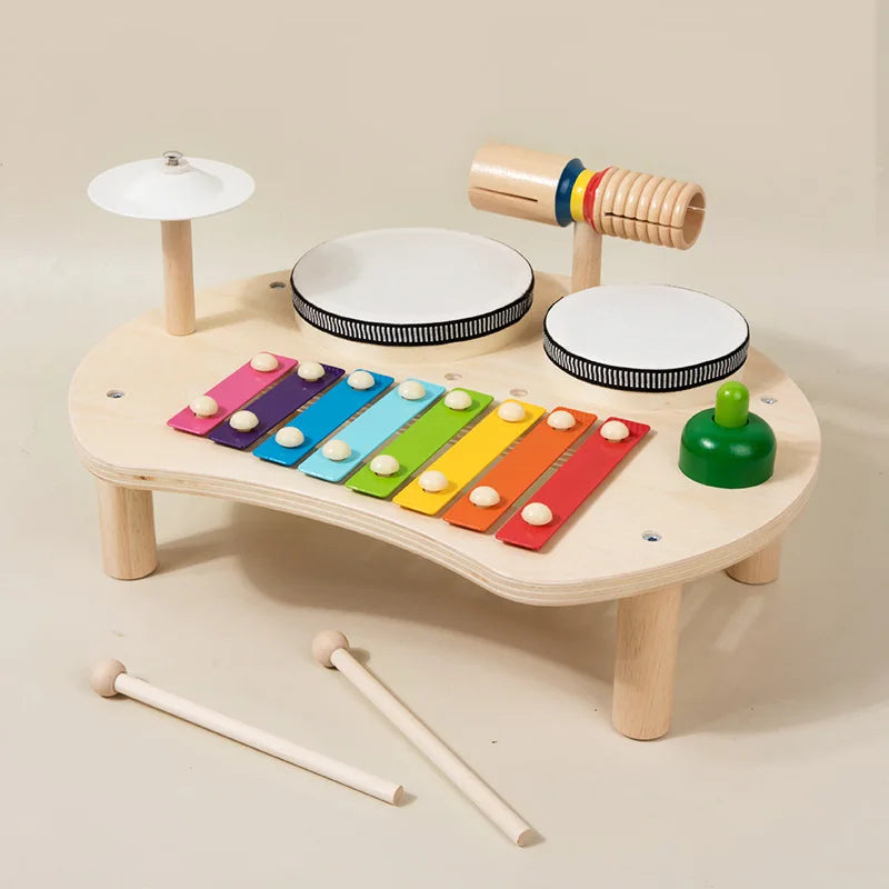 Wooden toy music set with colorful xylophone, drums, and other instruments on a beige background