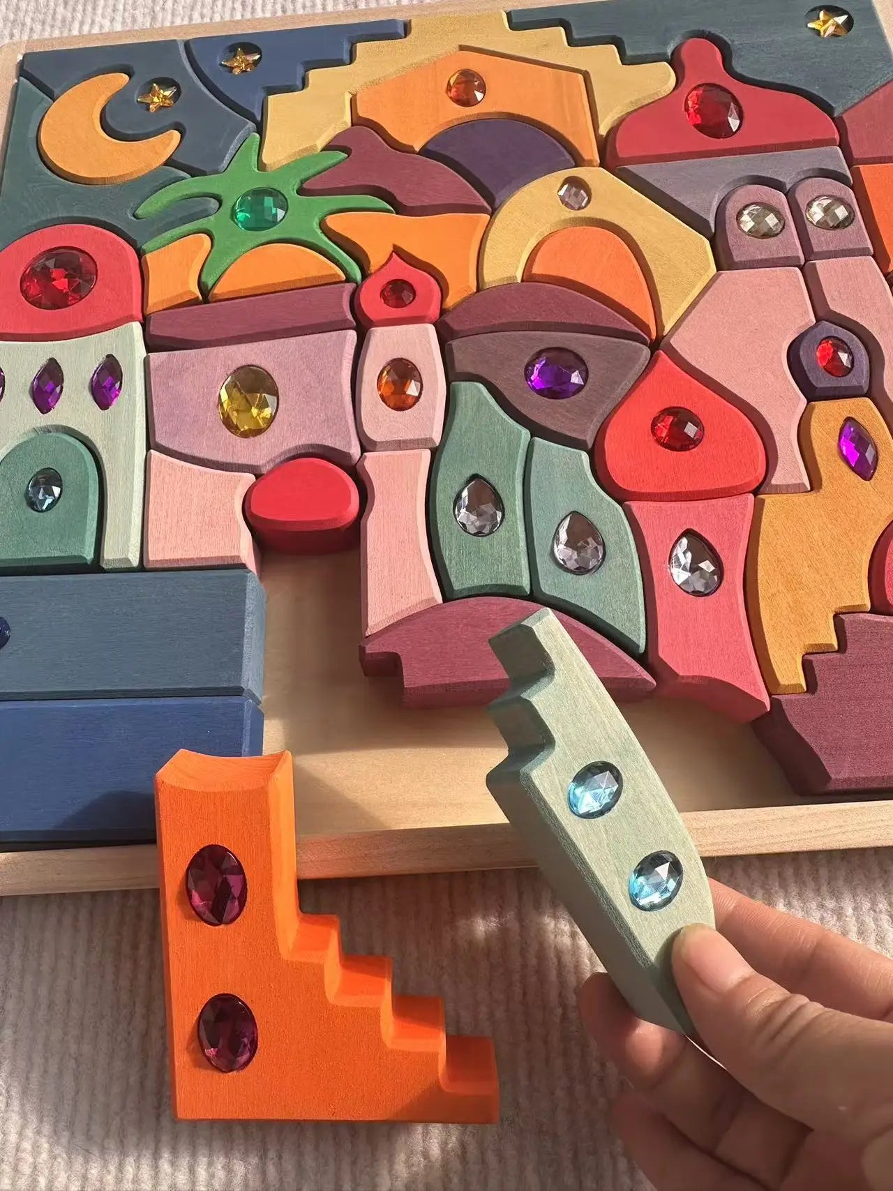 Colorful wooden puzzle with decorative stones held by a hand