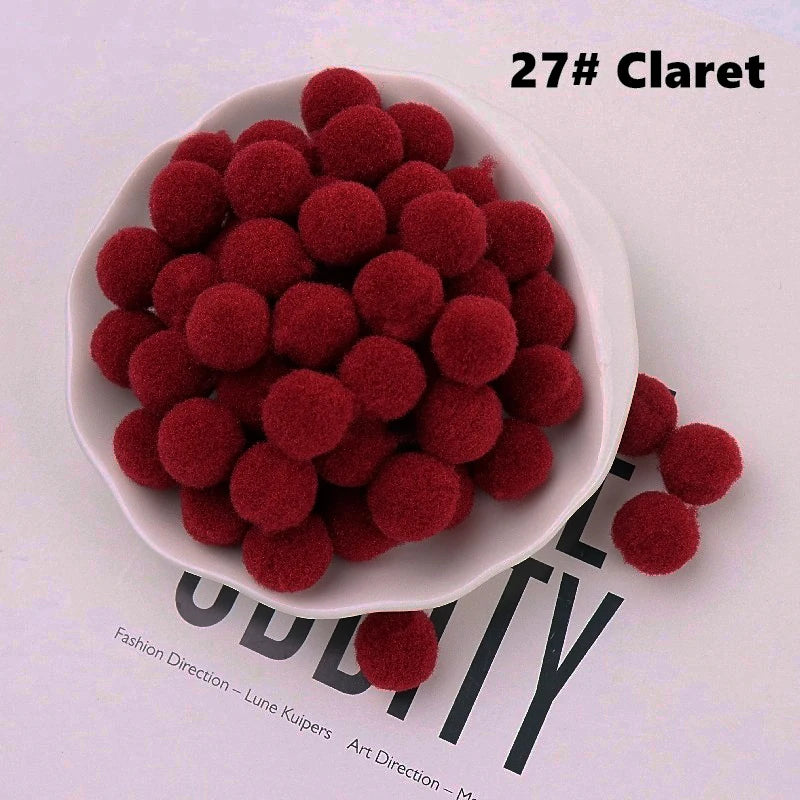 White bowl filled with claret red pom-poms on a magazine background