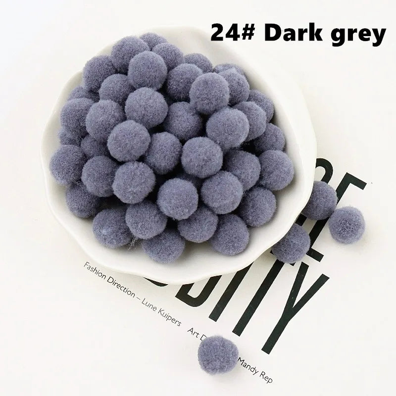Dark grey pom-poms in a white bowl on a magazine background