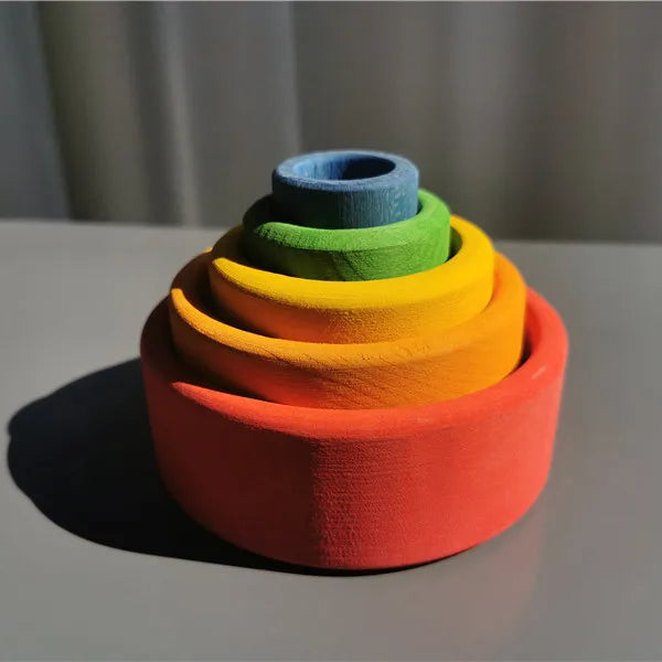 Stack of colorful wooden stacking bowls on a gray surface