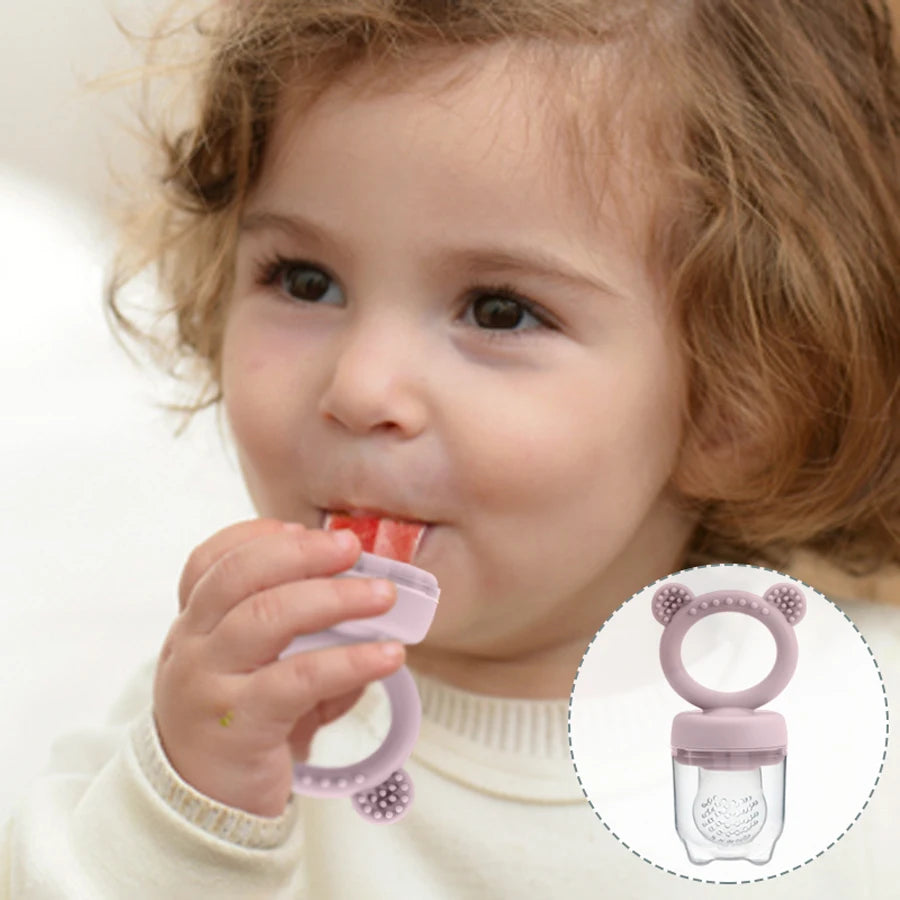Toddler eating fruit from a bear silicone food feeder