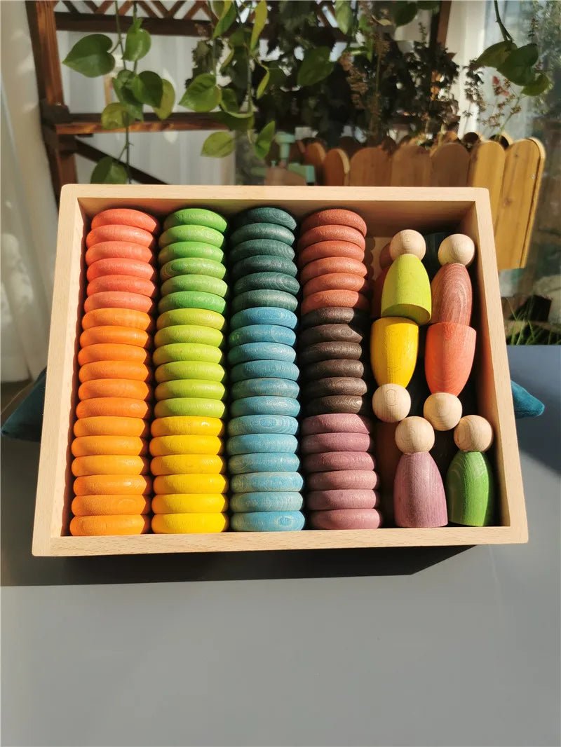 Montessori Rainbow Stacking Coins and Rings with Peg Dolls, featuring colorful wooden objects in a box, ideal for enhancing children's motor skills and imaginative play.