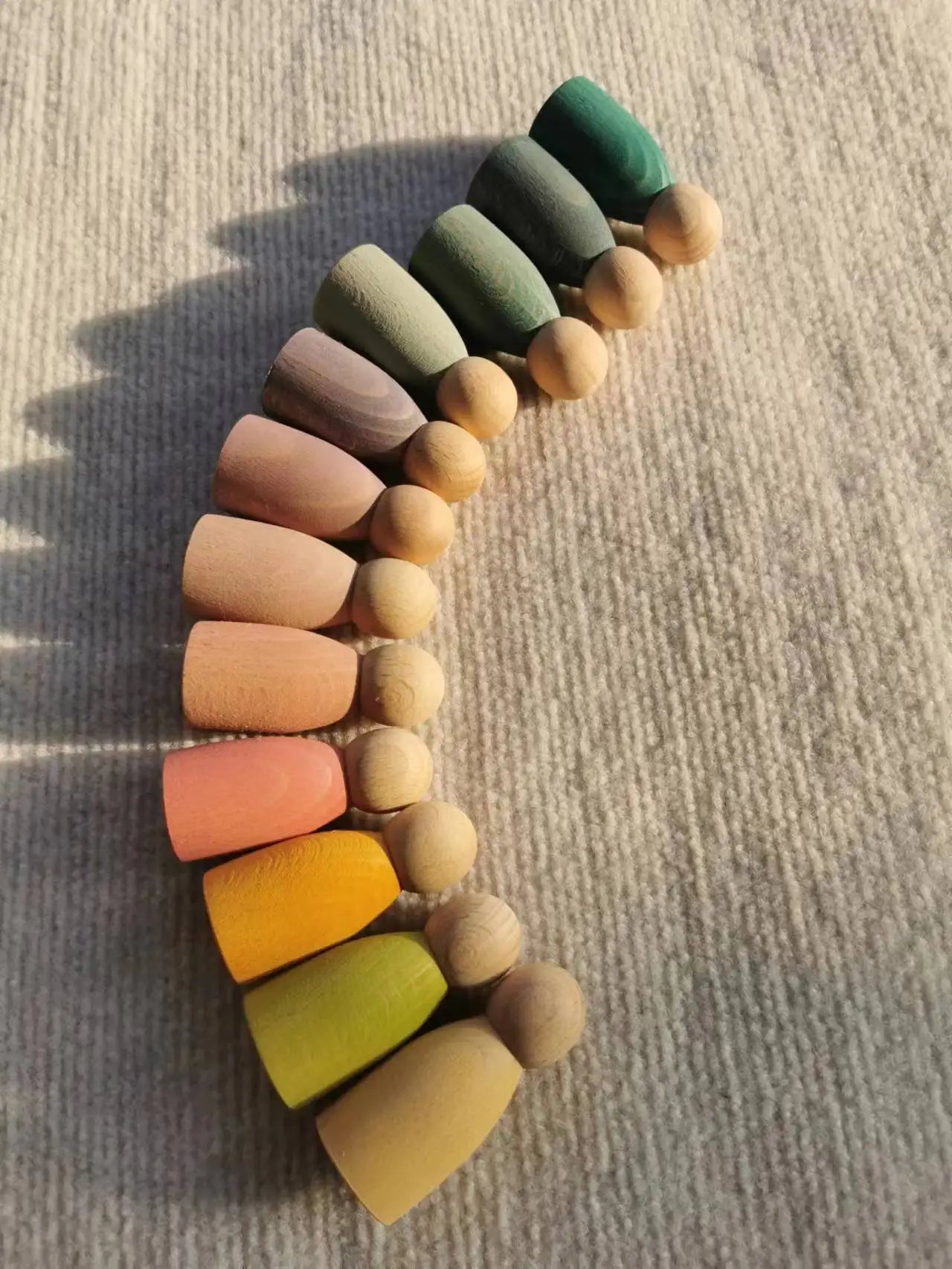 Montessori Rainbow Stacking Coins and Rings with Peg Dolls by Bajo, featuring wooden pegs and stackable components for developing fine motor skills and imaginative play.